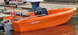 Das Elektromotorboot "Earl Elmo". Es ist leuchtend orange mit einem Bügel am Heck für Licht und hat einen schwarzen Steuerstand.